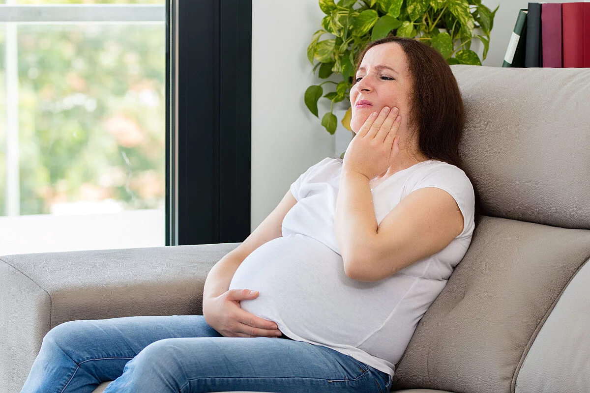 Donna incinta mostra dolore alla bocca