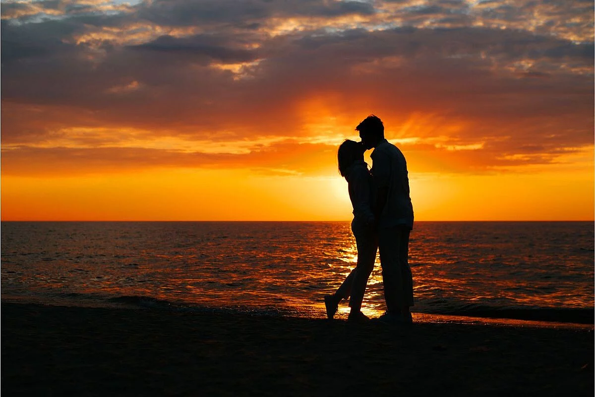 Immagine romantica di una coppia che si bacia in un tramonto sul mare