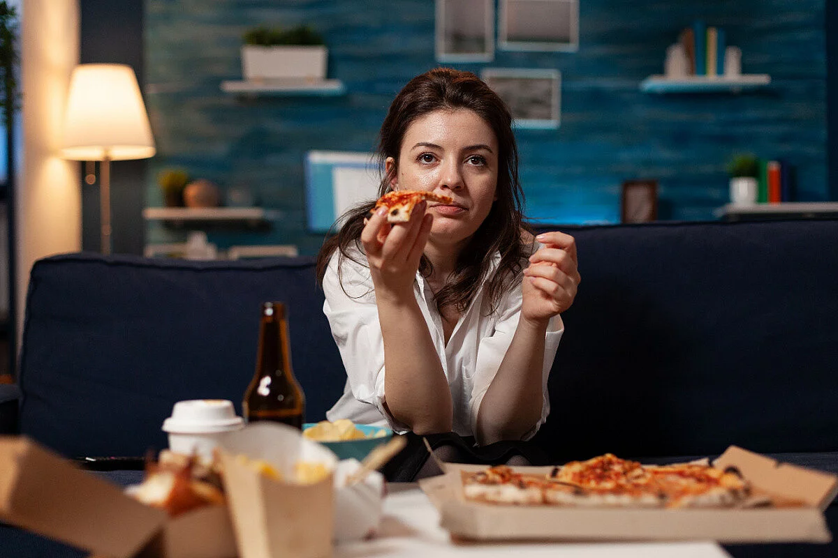 Donna che mangia pizza e patatine per nervosismo