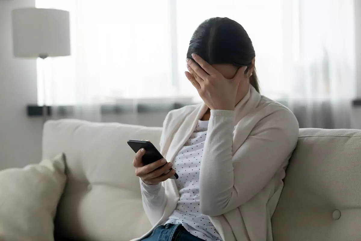 Donna che piange leggendo un messaggio al cellulare
