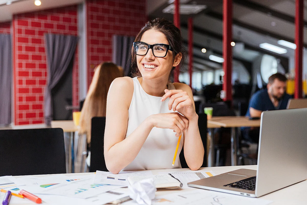 Donna sorridente sul luogo di lavoro di fronte ad un laptop